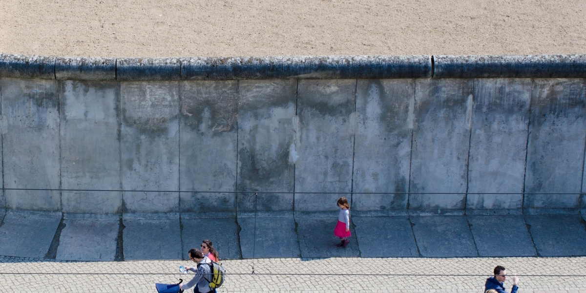 Child standing near the Berlin Wall. Photo via Flickr.
