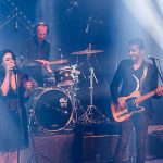 Ninet Tayeb sings into a mic and Dudu Tassa plays guitar onstage in a live concert photo