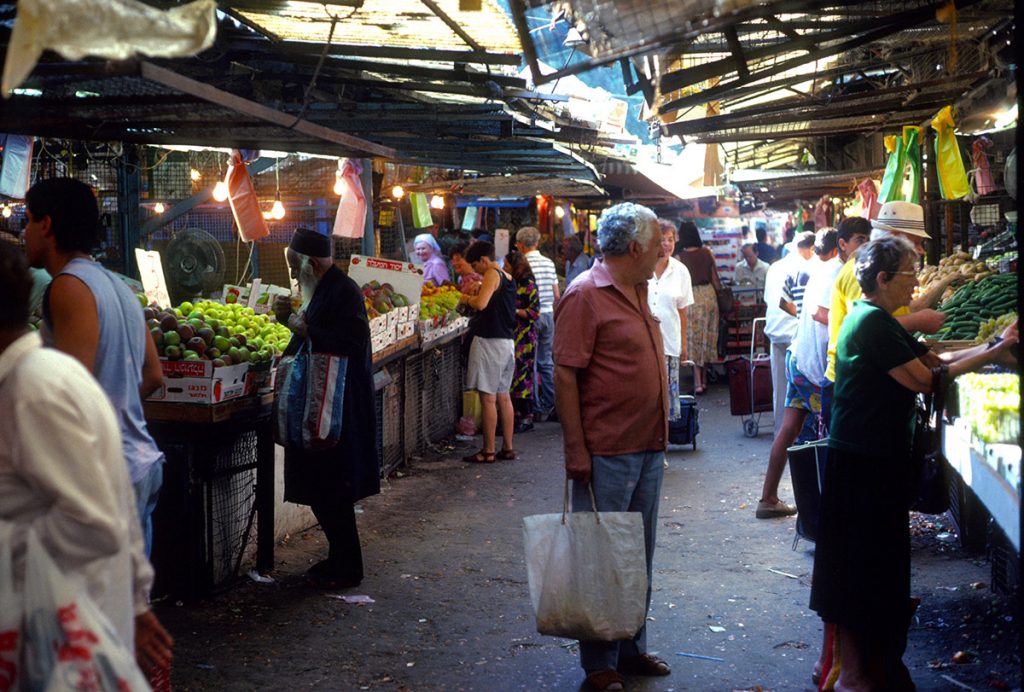 Shoppers purchase produce at stalls in a covered market