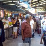 Shoppers purchase produce at stalls in a covered market