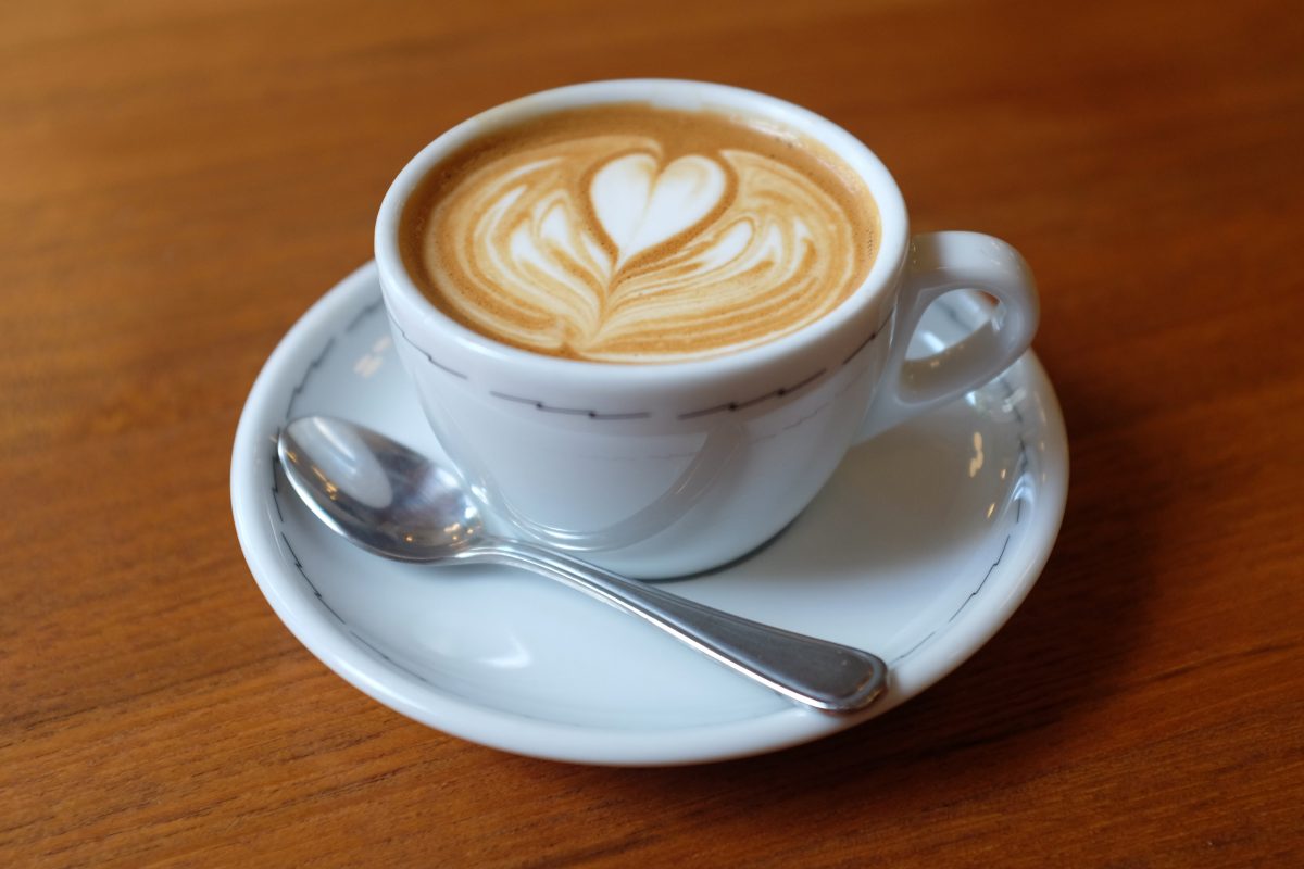 A cappuccino in cup and saucer with a heart-shaped design on top