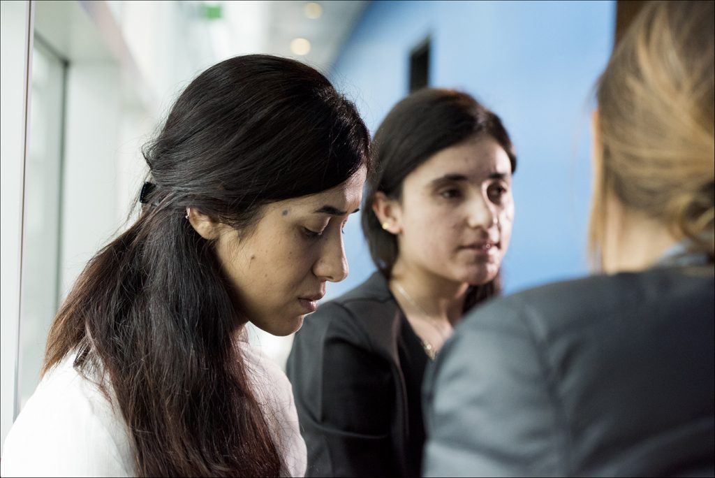 Photo showing two somber-looking Kurdish women in a hallway in discussion with someone off-camera