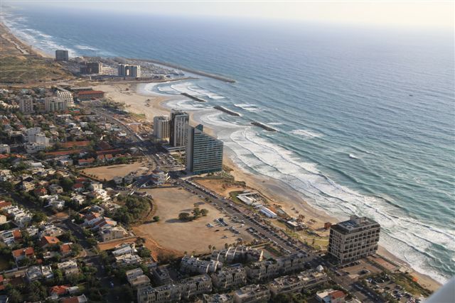 An aerial photo shows a small city alongside the beach and ocean