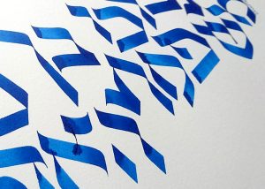 Color photo showing elegant calligraphy with Hebrew letters, made in blue paint on thick paper