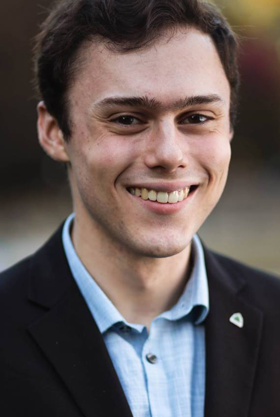 Portrait of Gabriel Epstein smiling, wearing a blue button-shirt and black suit jacket
