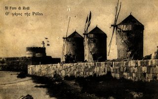 Old sepia toned postcard from Rhodes. Features three brick windmills in the foreground and a brick wall along a sea line.