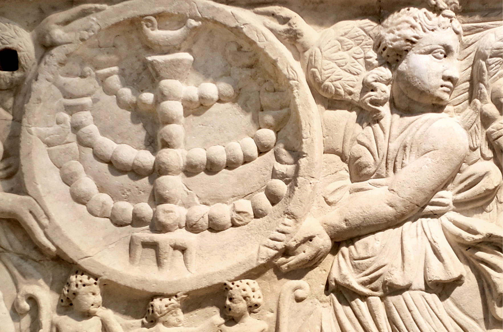 Ancient angelic figures carved in stone holding menorah