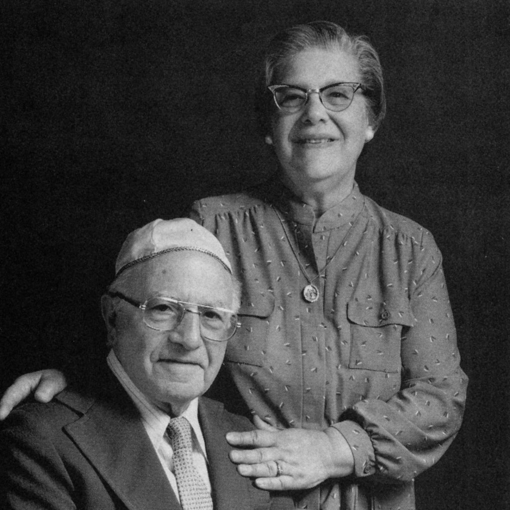 Black and white portrait of Bension and Lucy Maimon. Bension is seated and Lucy is standing next to him.