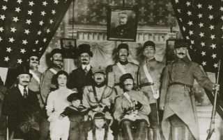 Studio photo of Sephardic family, men wearing Ottoman military outfits, with American flags as a backdrop