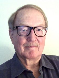 Portrait of Alan Dowty smiling wearing glasses and a black collared shirt