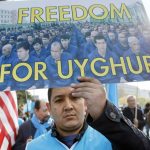 Man at protest holds up a "Freedom for Uyghurs" sign