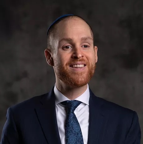 Rabbi Benjamin Hassan headshot in a suit against a grey background.