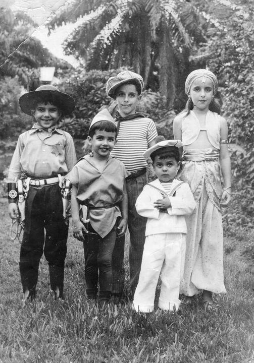 Black and white photo of five children dressed in costumes with trees in the background.