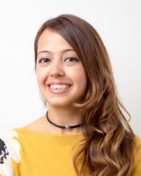Melike Yucel Koc headshot. She is smiling and wearing a yellow shirt. Her brown hair is pulled to her right side. The background is white.