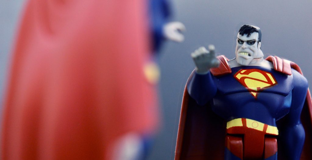 Figurine of Bizarro Superman with an inverted S on chest pointing at regular Superman