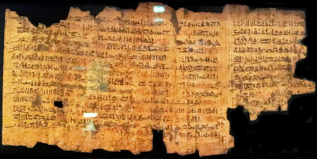Aged, fragmented papurys scroll with black and red Egyptian script