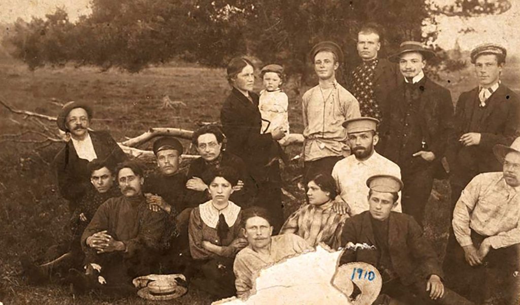 Sepia photograph of men and women in their twenties and thirties gathered in a field