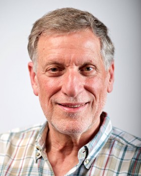 portrait of Joel Migdal smiling wearing plaid dress shirt