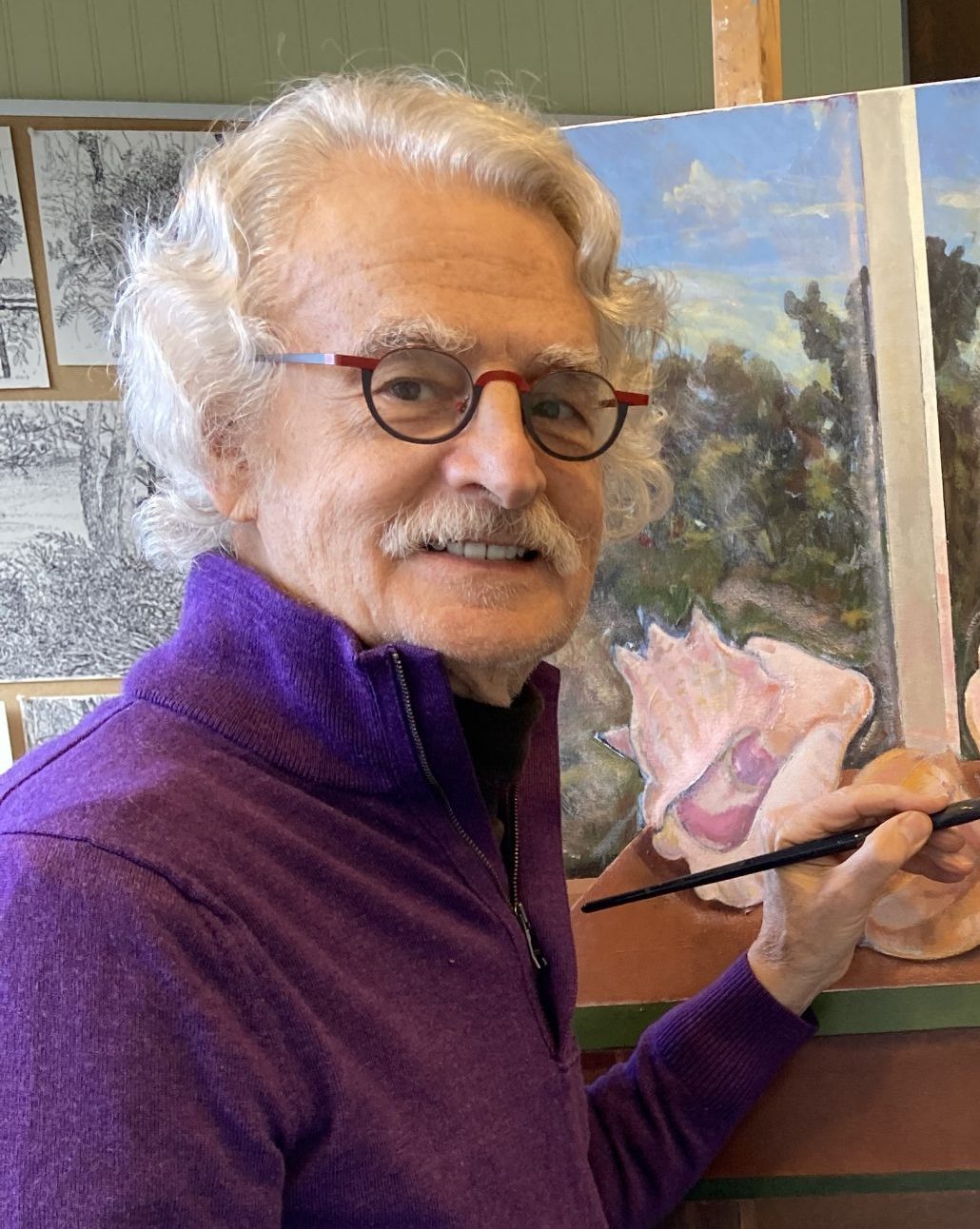 Harry Naar wearing purple quarter zip, painting, looking back and smiling