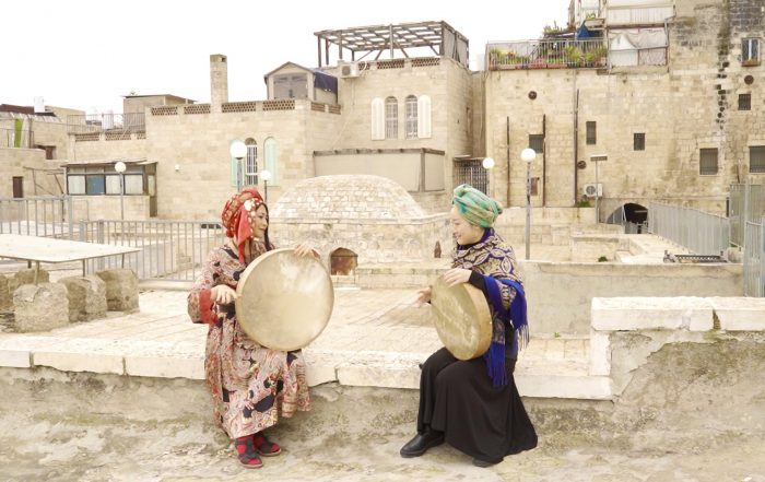 Ke Guo and Japanese musician Okaniwa Yayoi wearing bright traditional clothing and playing instruments in Jerusalem's Old City