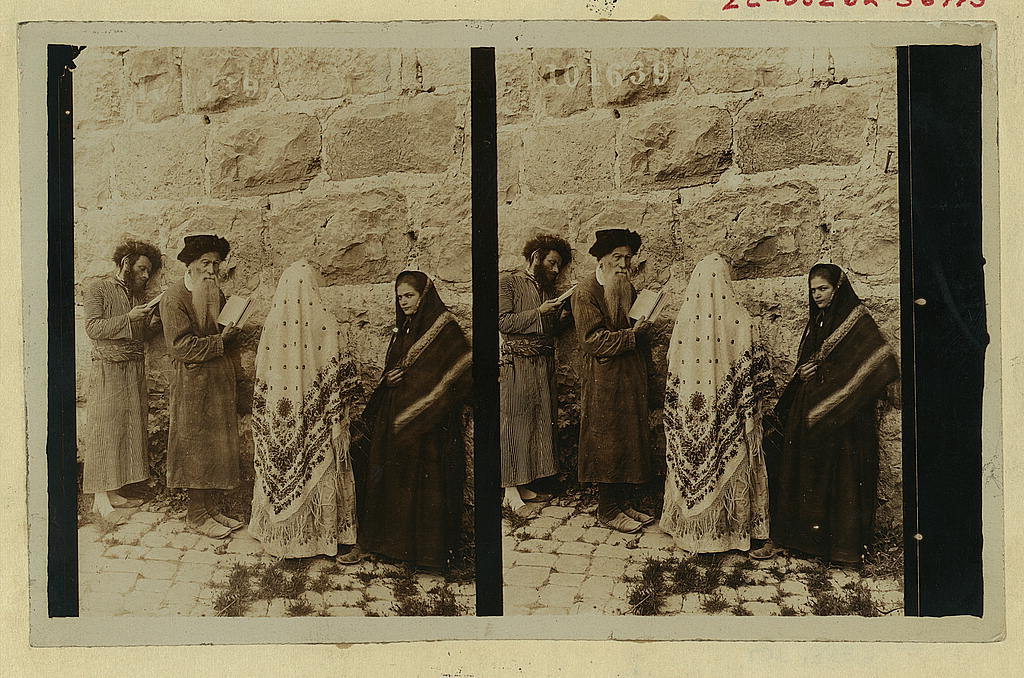old sepia-toned photo of 2 men and 2 women praying at western wall