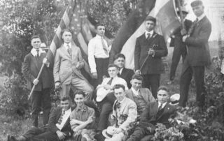 Young Armenian men in suits smiling and holding 2 large Armenian and American flags