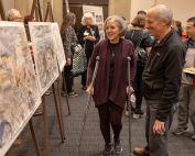 An older couple admiring Harry Naar's paintings at Muestros Artistas
