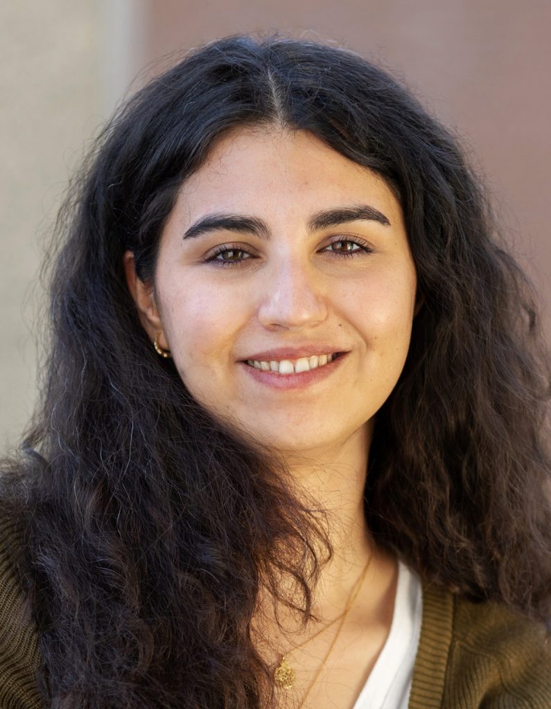 Büsra Demirkol smiling in sweater, outdoors