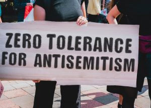 two individuals holding a large sign that reads, "zero tolerance for antisemitism"