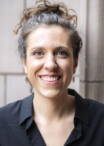 Joana Bürger smiling, sandstone campus building in background