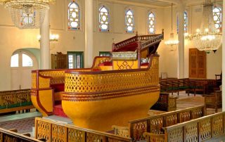 Synagogue interior, with boat-shaped raised platform (bima) in the center and windows with Star of David pattern