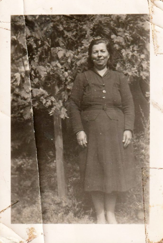 Black-and-white photo of a woman in a dark formal dress, vines behind her