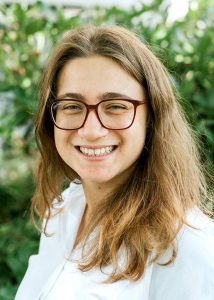 Alexandra Ritsatos, smiling, outdoors, leaves in background