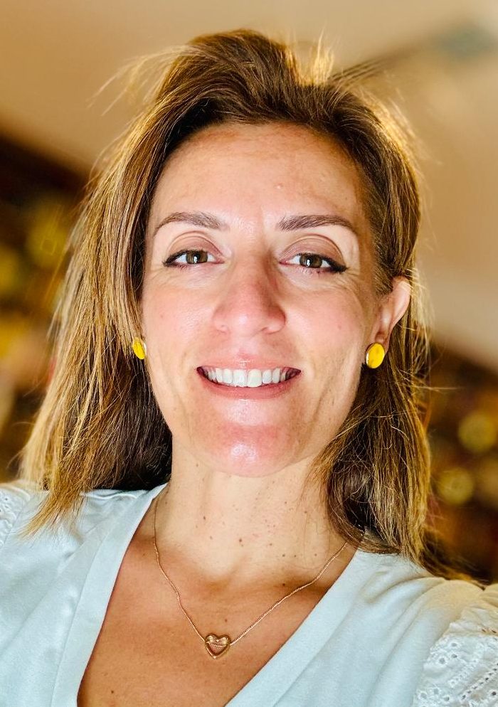 Maria Papavasilopoulou smiling, bookshelves in background