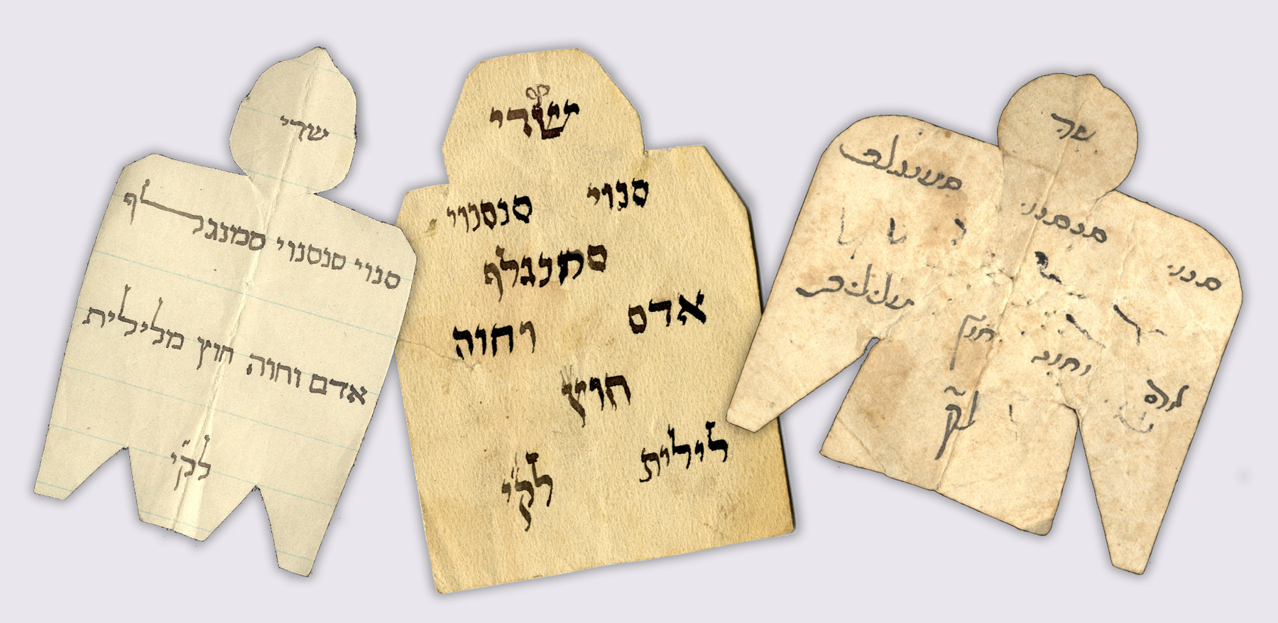 Three angel-shaped paper amulets with handwritten Hebrew characters