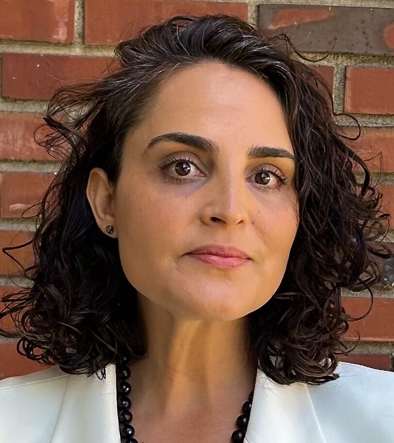 Gilah Kletenik in blazer, brick wall in background