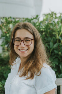 Woman wearing white shirt with glasses and long hair.