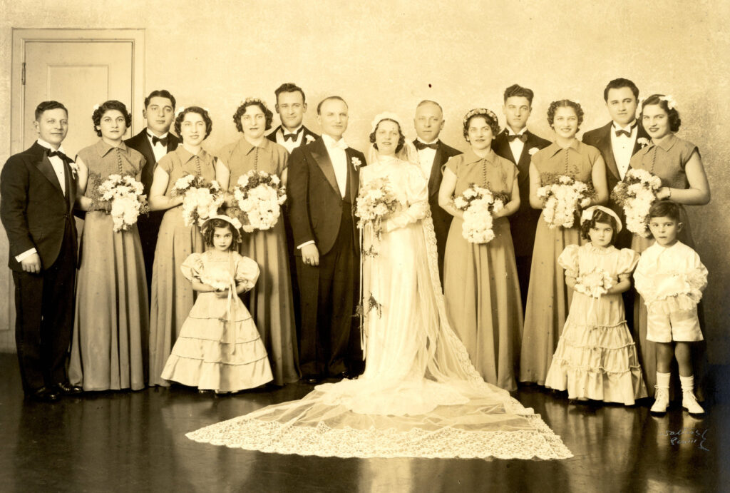 Sepia photograph of large wedding party with bridesmaids, groomsmen, flower girls and a ring bearer