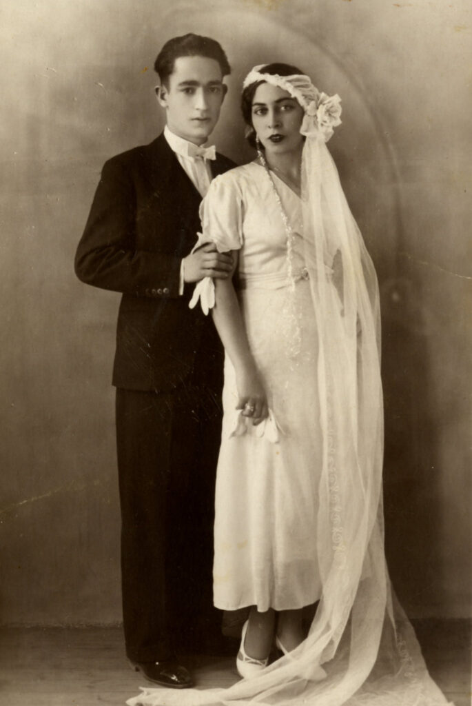 Black and white portrait of bride in elegant dress wearing veil head-dress that reaches the floor and groom in suit