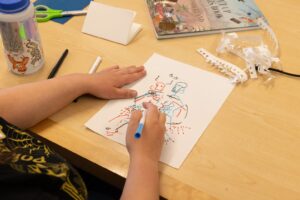 Overlooking a student drawing on a piece of paper at a table