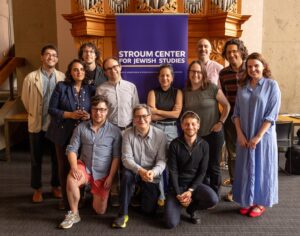 A group of 12 faculty posing behind a banner for the Stroum Center for Jewish Studies