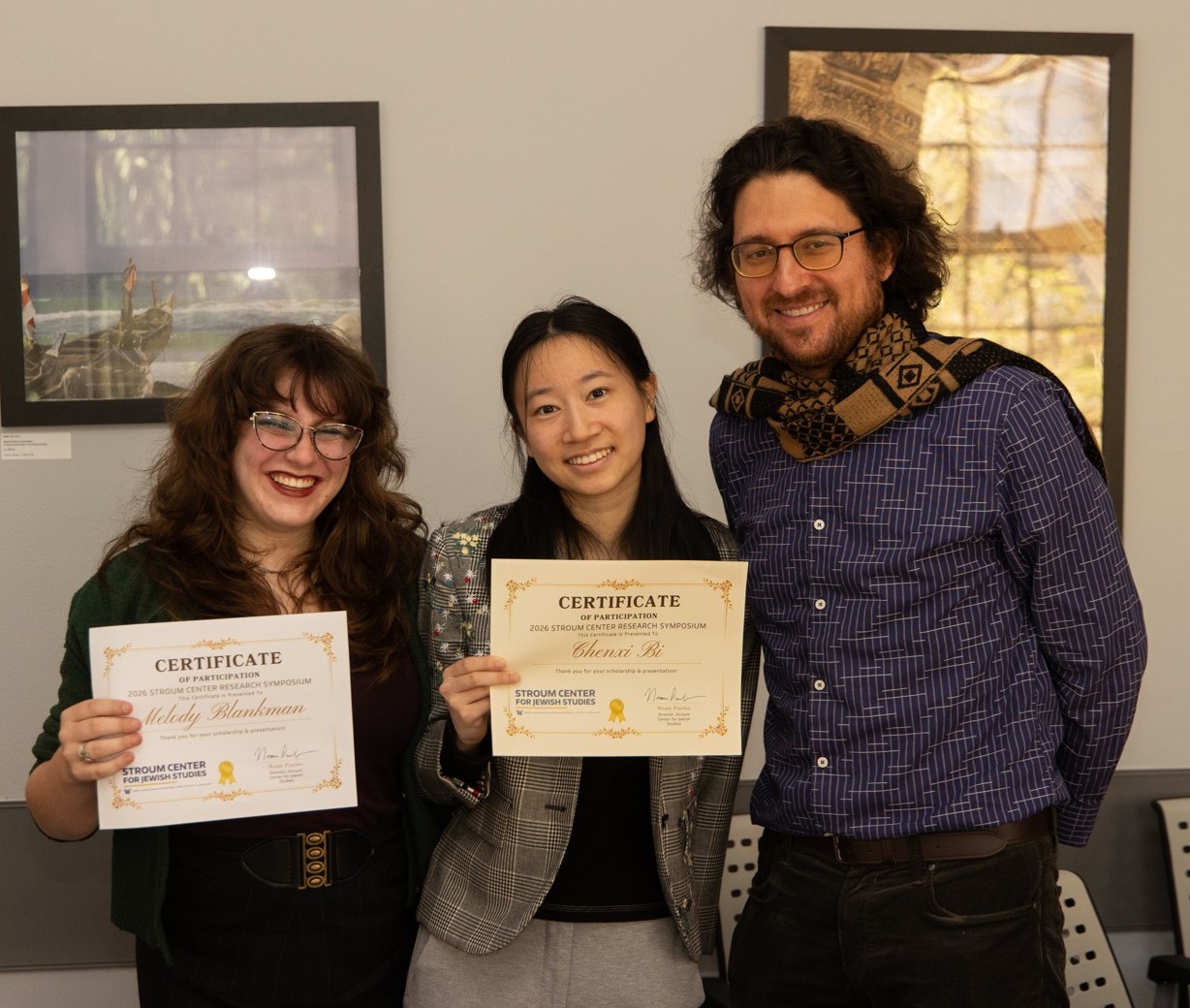 Three people smile for a photo indoors; two hold certificates of participation from the 2026 Stroum Center Research Symposium.