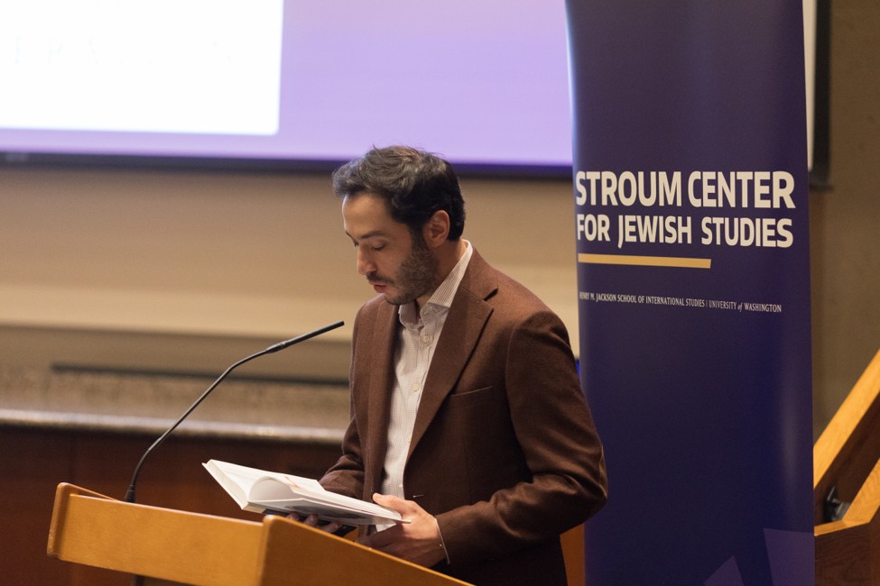 A speaker reads from a book at a lectern during a Stroum Center for Jewish Studies event.