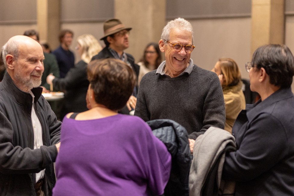People gather in small groups for conversation during a post-event reception.